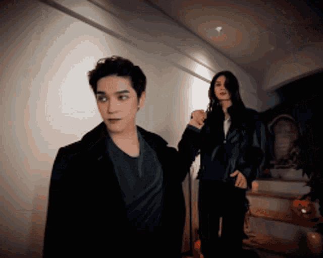 a man and a woman are standing in a hallway holding hands
