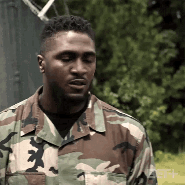 a man in a military uniform is standing in front of a fence with the bet logo in the corner