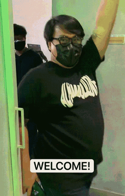 a man wearing a mask and a black shirt that says welcome