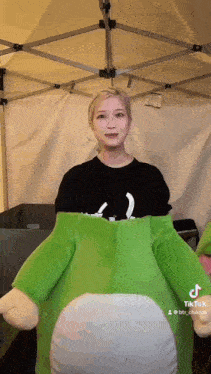a woman is holding a green stuffed animal .