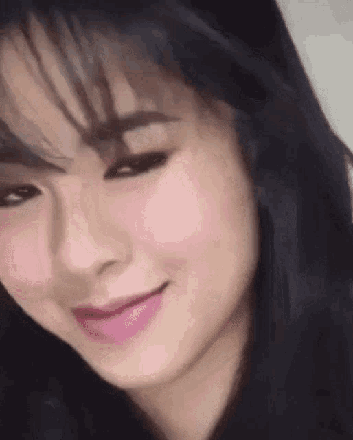a close up of a woman 's face with a pink lip and black hair .