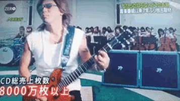 a man is playing a guitar in front of a sign that says zero on it