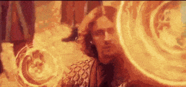 a man is surrounded by a circle of fire and looks at the camera .