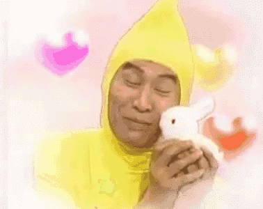 a man in a yellow costume is holding a stuffed bunny rabbit .