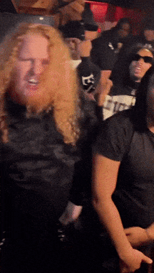 a man with a beard wears a black shirt with the letter e on the front