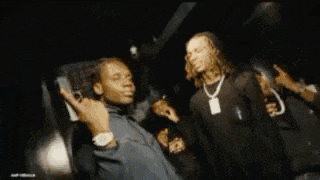 a man is holding a gun in front of his face while another man stands behind him .