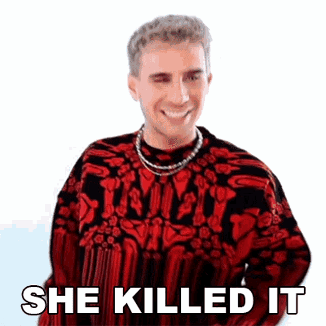 a man wearing a red and black sweater and a necklace is smiling and says `` she killed it '' .
