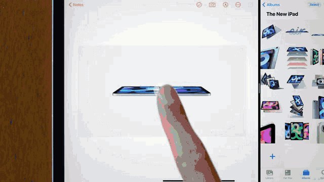 a person 's finger is pointing at a picture of an ipad