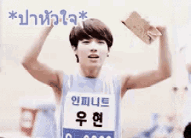 a young man wearing a blue tank top is holding a bottle of water over his head .