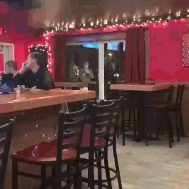a group of people are sitting at tables in a bar
