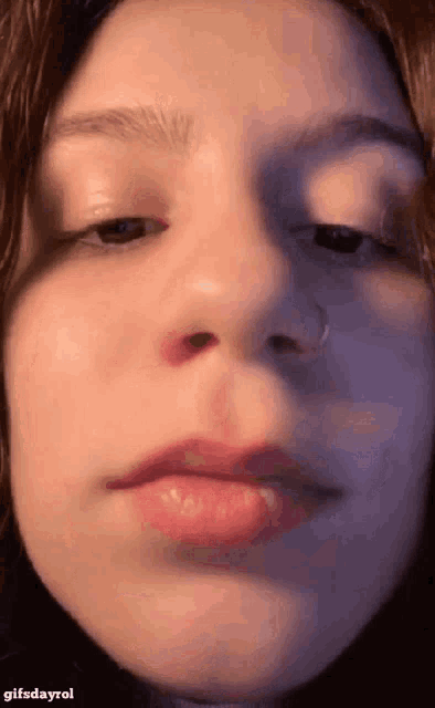 a close up of a girl 's face with a nose ring on it