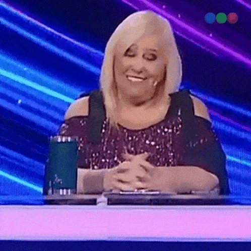 a woman in a sequined top is sitting at a table with her hands folded