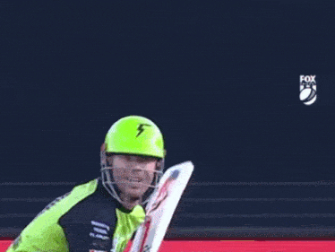 a cricket player is wearing a green helmet and a green shirt that says fox sports on it .