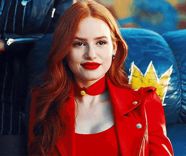 a woman with red hair and red lipstick is wearing a red jacket .