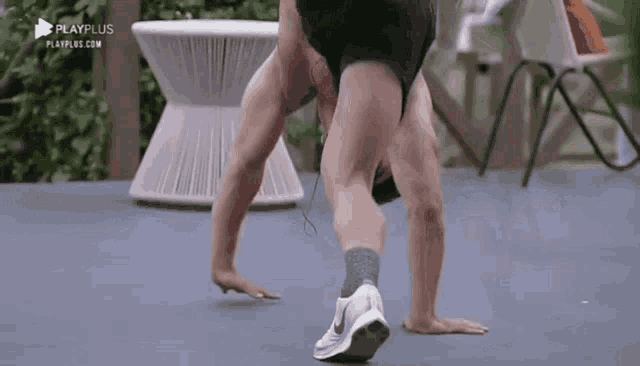 a man is doing a handstand in front of a playplus advertisement