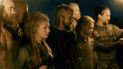 a group of people are standing in a line and one of them has a beard .