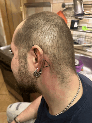 a man with a triangle tattoo on his back of his neck