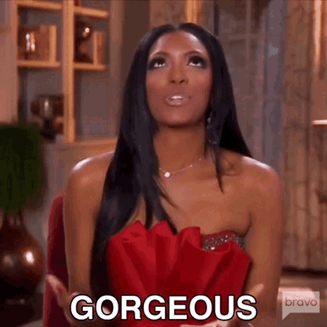 a woman in a red dress is sitting in a chair and says gorgeous .