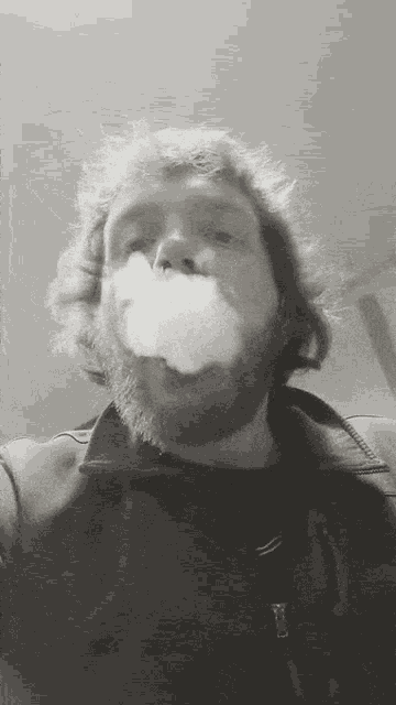 a man with a beard is blowing a cloud of smoke out of his mouth