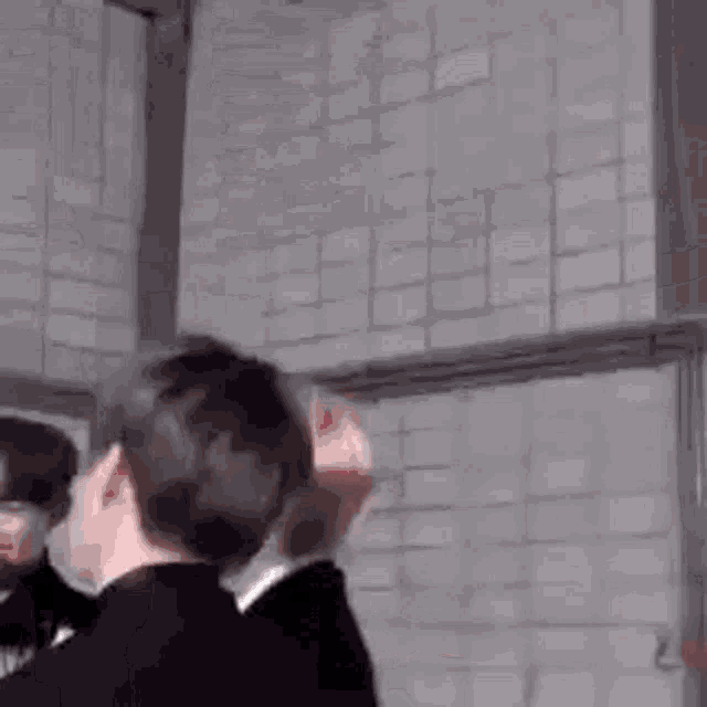 a group of people are standing next to each other in front of a wall .