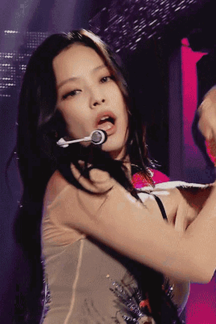 a close up of a woman singing into a microphone on stage