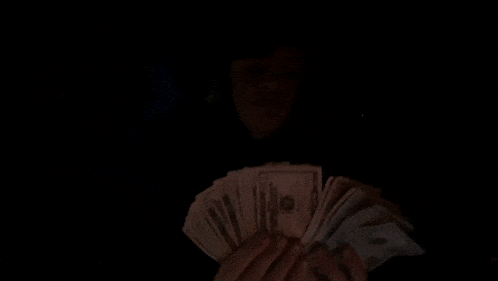 a man wearing headphones holds up a fan of 20 dollar bills