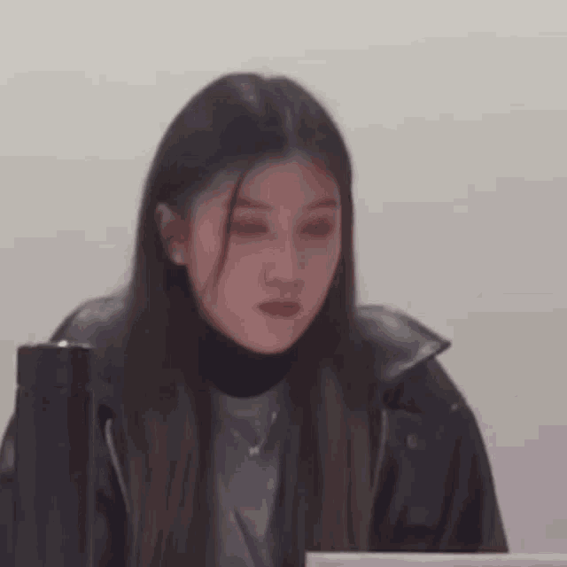 a woman in a black leather jacket is sitting at a table with a laptop .