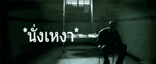 a man is sitting in a chair in a dark room with chinese writing on the wall
