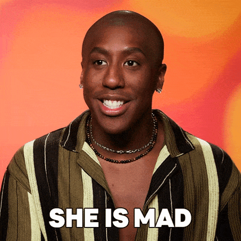 a man wearing a striped shirt and a necklace smiles and says she is mad