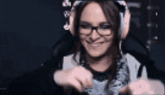 a woman wearing headphones and glasses is sitting in a chair playing a video game .