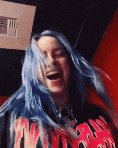 billie eilish is wearing a black shirt with flames on it and has blue hair .
