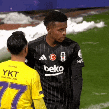 a man in a beko jersey stands next to another man in a yellow jersey