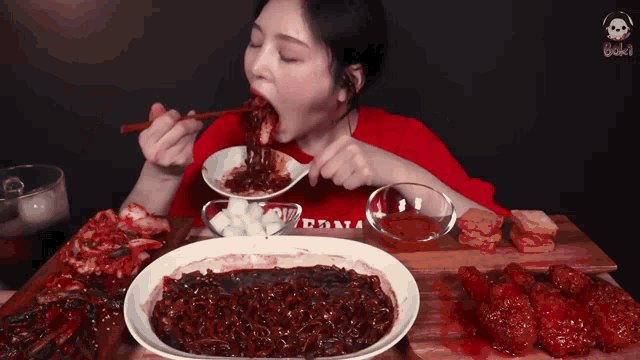 a woman wearing a red shirt that says california is eating a plate of food