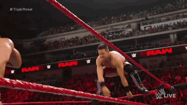 two men are wrestling in a wrestling ring while a referee looks on .