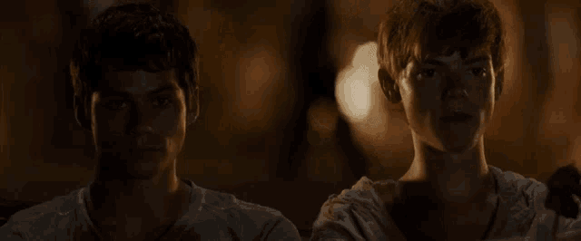 two young men are sitting next to each other in a dark room at night .