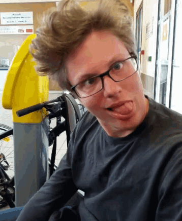 a man wearing glasses sticks his tongue out