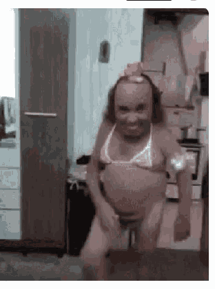 a woman in a bikini is dancing in a kitchen while sitting on a stool .