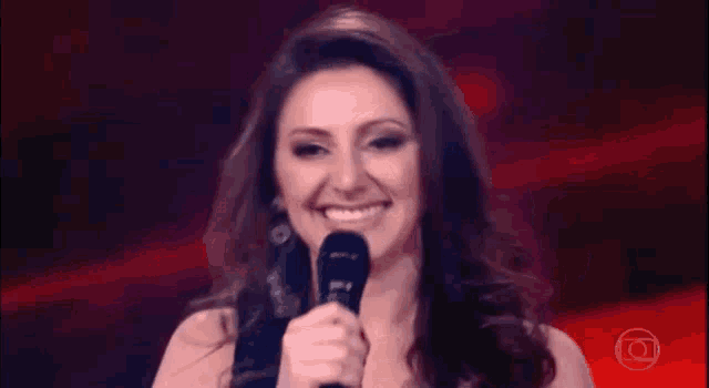 a woman is smiling while holding a microphone in front of her face .