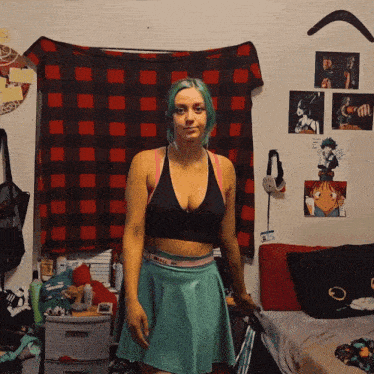 a woman with green hair is standing in a room with a plaid blanket