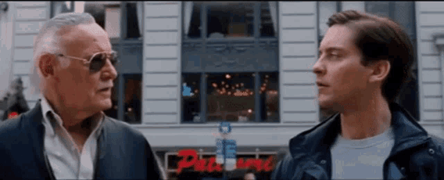 two men are standing in front of a building that has the word pleasure on it
