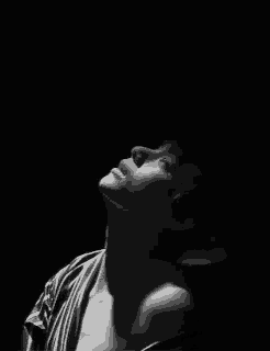 a black and white photo of a woman looking up in the dark