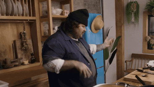 a man in a kitchen with a hat on his head