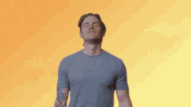 a man in a grey shirt is covering his eyes with his hand