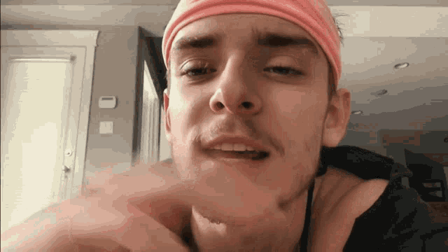 a young man wearing a pink headband looks at the camera .