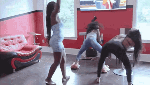three women are dancing in a living room in front of a television .