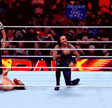 a man is kneeling in a wrestling ring with a sign that says judgement day runs wwe .