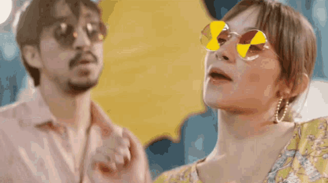 a man and a woman wearing sunglasses are looking up .