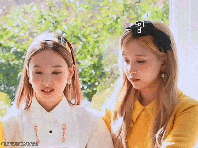 two girls are standing next to each other and one has a headband with the letter p on it .
