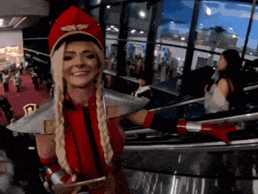 a woman in a red costume is smiling in front of a large window