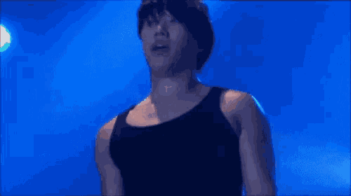a man in a black tank top is standing on a stage .